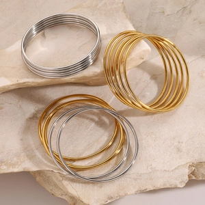 Minimalist stacked gold and silver stainless steel bangles on natural stone base