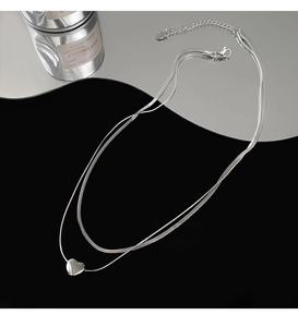 Detailed macro shot of a double-layered silver heart pendant with elegant snake chain