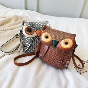 Detailed view of fashion owl-shaped crossbody bags with feather print on white bedding