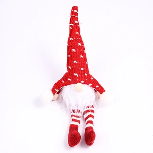 Close-up of a red knitted Christmas gnome with a white heart pattern and striped legs