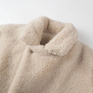 Dettaglio della morbida trama in pile color crema sul rever di una giacca alla moda