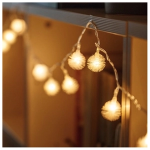 Close-up of fluffy warm white pom-pom LED fairy lights for cozy interior decoration