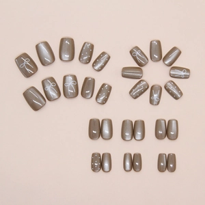 Detail view of short square press-on nails with hand-painted bow and polka dot patterns