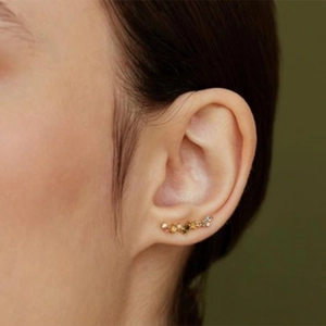 Close-up of curved gold crawler earrings with multi-colored zircon stones on a model