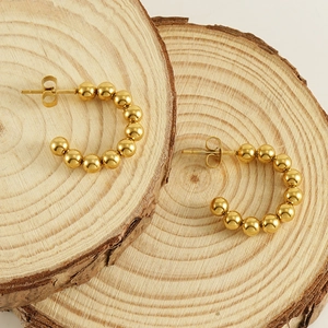 French vintage 18K gold beaded hoop earrings displayed on natural wood slices
