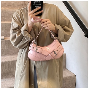 Close-up of pink patent leather Y2K shoulder bag with metal eyelets and buckle details