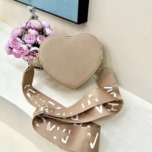 Detailed view of heart-shaped crossbody bag with wide jacquard strap and gold hardware