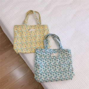Gros plan de sacs fourre-tout en coton fleuri bleu et jaune sur une surface douce