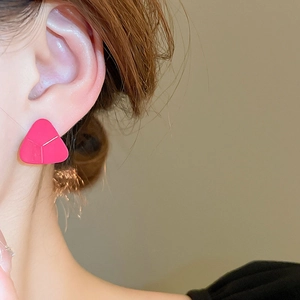 Vue détaillée d'une boucle d'oreille géométrique triangle rose portée par un mannequin