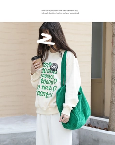 Detail of dark green corduroy tote bag with striped texture and vintage lettering sweatshirt
