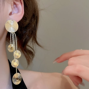 Detail of gold geometric round earrings with tassels worn by model for elegant style
