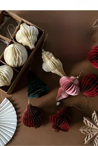 Close-up of assorted honeycomb paper Christmas tree and star ornaments in cream and red