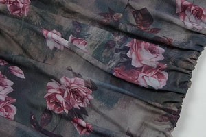 Detail of charcoal grey sheer mesh fabric with vintage rose floral prints and pleated texture