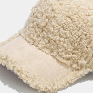 Detailed macro shot of beige faux shearling texture and suede brim on the baseball cap