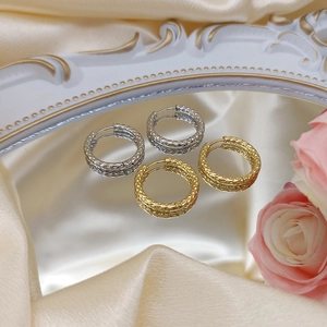 Detail view of textured gold and silver hoop earrings on elegant satin with flowers