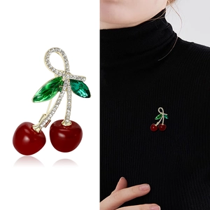 Cute cherry brooch with red fruit and green crystal leaves on a black sweater