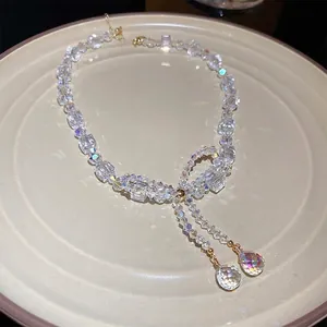 Elegant crystal bow necklace with double water drop pendants on a beige ceramic plate