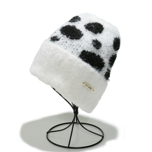 Detailed texture of cow print knit beanie featuring a premium gold metallic UNI-MBK label