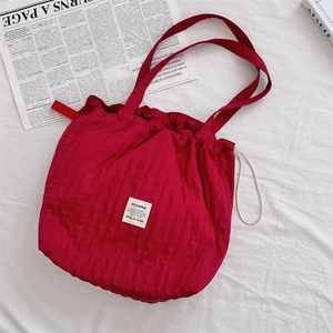 Gros plan du sac cabas rouge à rayures avec cordon de serrage et étiquette de logo blanche