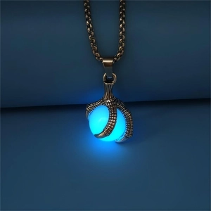 Close-up of vintage bronze dragon claw holding a luminous blue glowing orb pendant