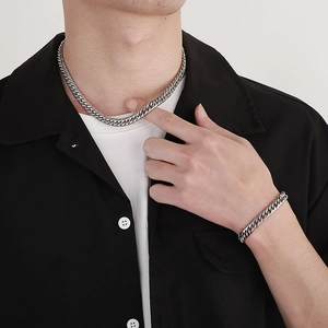 Ensemble collier et bracelet gourmette en acier inoxydable argenté porté par un homme