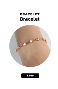 Detail of gold chain bracelet featuring pink heart-shaped evil eye charms on a wrist