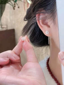 Close-up of snowflake silver drop earrings with zircons showing the delicate hanging detail