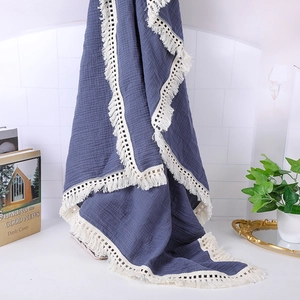 Detail of dark blue muslin baby blanket with cream lace fringe and wrinkled texture