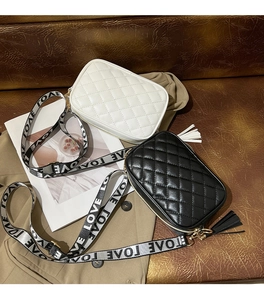 Detail of quilted crossbody bags with embroidered LOVE wide straps and fringe tassels