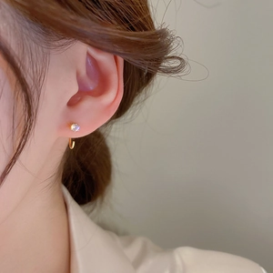 Detail shot of a minimalist gold hoop earring with a sparkling zircon on the model ear