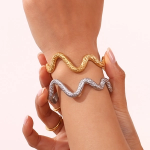 Detail of 18K gold and silver plated wavy hammered texture open bangles on wrist
