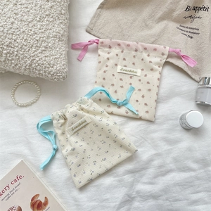 Detailed close-up of corduroy floral drawstring bags with Sozakka brand label on white fabric
