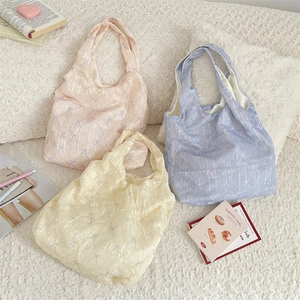 Vue détaillée de dessus de trois sacs cabas à nœuds texturés en rose, bleu et jaune