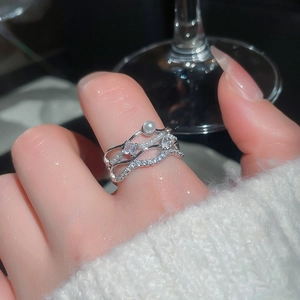Macro shot of a layered silver wave ring with zircons and a pearl worn on a finger