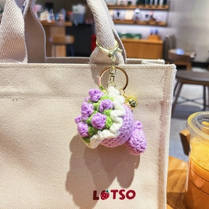 Handmade crochet flower bouquet keychain with purple blossom and bell on canvas bag