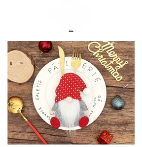 Close-up of gnome Christmas cutlery holder on a plate with golden fork and knife