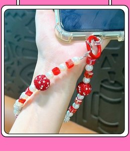 Gros plan de la dragonne de téléphone avec cristaux rouges, perles et boules strass
