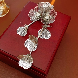 Detailed close-up of silver floral tassel earrings with rhinestones on a wooden box