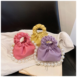 Detailed view of pink, yellow, and purple ruched mini bags with pearl beaded handles