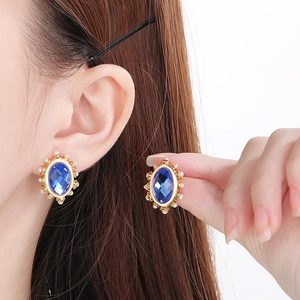 Detail of vintage gold earring with oval blue stone and surrounding white pearls