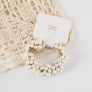 Detail of elegant handmade pearl scrunchie with cream beads on display card