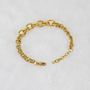 Detail of gold stainless steel layered chain bracelet with lobster clasp on white fur