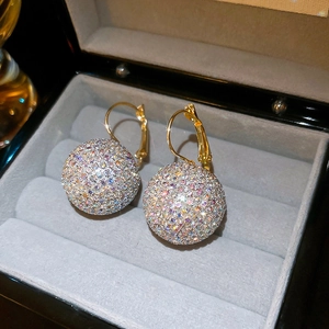 Close-up of golden dangle earrings featuring a colorful crystal-encrusted ball design