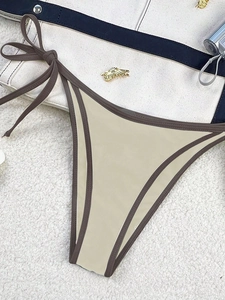 Detail of minimalist beige bikini bottoms with contrast coffee binding and adjustable side ties