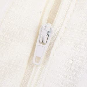 Macro shot of white invisible zipper on linen texture fabric for V-neck wide-leg suit set