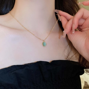 Close-up of gold oval cat eye stone necklace worn on a model's collarbone