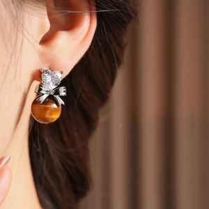 Close-up of model wearing heart zircon bow earrings with tiger eye stone bead