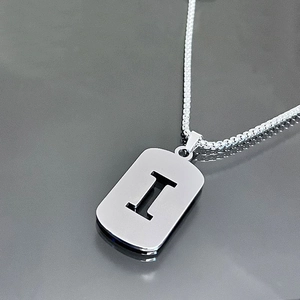 Gros plan d'un collier en acier argenté avec pendentif rectangulaire lettre I évidée