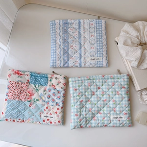 Vue détaillée de pochettes en coton matelassé aux motifs floraux et à carreaux bleus