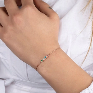 Close-up of rose gold bracelet with four colorful rhinestones on a woman wrist